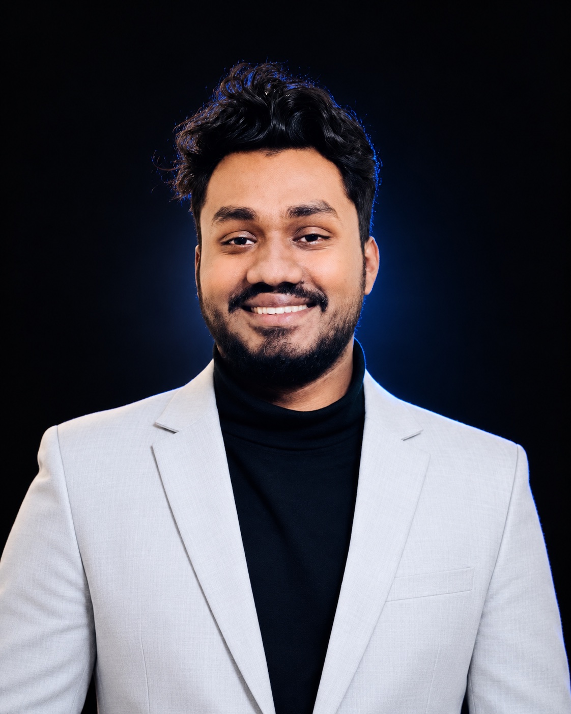 Amran H. Fahim, smiling in a light blazer and black turtleneck